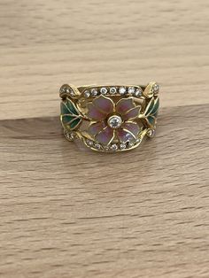 This exquisite Masriera Art Nouveau ring showcases asymmetrical brilliant cut diamonds set in 18kt yellow gold with plique à jour enamel accents. The vintage piece features a multicolor design and is signed by the artist. The ring is size 8.5 and has a pave setting style, making it perfect for any occasion. The Loupe Clean gemstone clarity grade and Excellent cut grade give the diamonds a stunning sparkle. This handmade, natural creation is a one-of-a-kind addition to any fine jewelry collection. Look at our pictures you will receive what you see. Also note that these are all hand finished that been said even if these where mass produced which they are not they would all look different the craftsmanship is unique in each one this is one of our many unique pieces of jewelry we have to sell Enamel Rings Vintage, Art Nouveau Wedding Ring, Art Nouveau Rings, Edwardian Rings, Art Deco Jewelry Rings, Vintage Trinkets, Cottagecore Wedding, Art Nouveau Weddings, Art Nouveau Ring