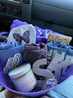 a purple basket filled with personal items in the back of a car's dashboard