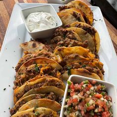 tacos and salsa on a white platter with sour cream in the back ground