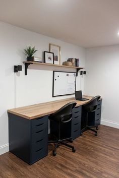 an empty office with two desks and shelves on the wall above them, along with black chairs