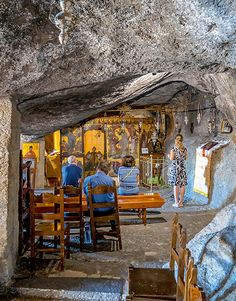 a group of people sitting at wooden tables in a cave