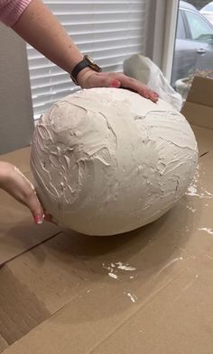 a person is making a large ball out of paper mache and plastic wrapper