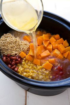 a bowl filled with beans, carrots, corn and other ingredients being poured into it