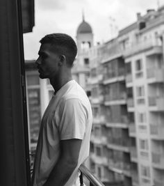 a man standing on top of a balcony next to tall buildings