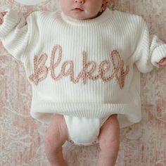 a baby wearing a sweater with the word baked written on it in front of a balloon