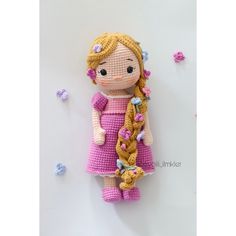 a small doll with long blonde hair wearing a pink dress and holding a flower in her hand