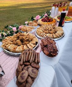 a table topped with lots of different types of food next to flowers and plates filled with pastries