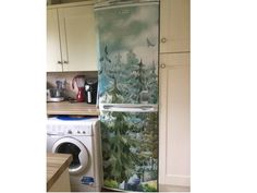 a refrigerator with a painting on it in a kitchen next to a washer and dryer