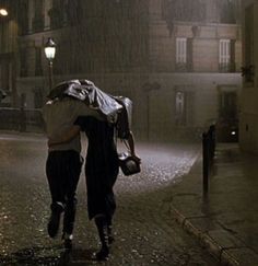 two people walking down the street in the rain with umbrellas over their heads,