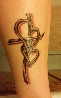 a tattoo on the leg of a woman with a cross and heart shaped arrow in it