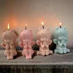 three candles with little angel figurines sitting on top of each other in front of a wall