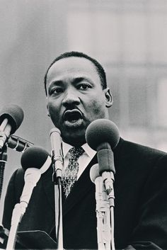 a black and white photo of martin luther king speaking into microphones