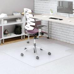 an office area with a desk, chair and computer monitor on the wall next to it