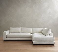 a white couch sitting on top of a hard wood floor next to a gray wall