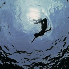 a man swimming in the ocean with his back to the camera