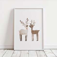 two deer standing next to each other in front of a white wall with wood flooring