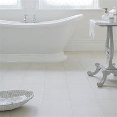 a white bath tub sitting in a bathroom next to a table with a towel on it