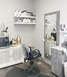 a salon chair in front of a mirror and shelves filled with hair care products on top of a hard wood floor