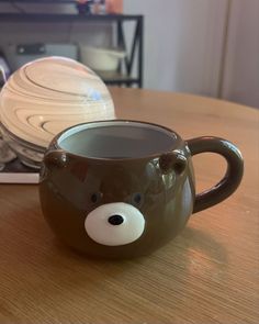 a coffee mug with a bear face on the inside sits on a table in front of a stack of plates