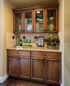 a kitchen with wooden cabinets and marble counter tops, along with hardwood flooring that matches the walls