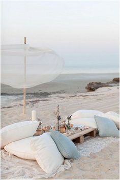 two pillows are laying on the beach and one pillow has been made into a picnic table