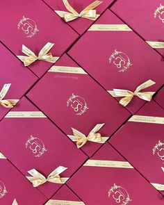 many pink boxes with gold ribbons on them