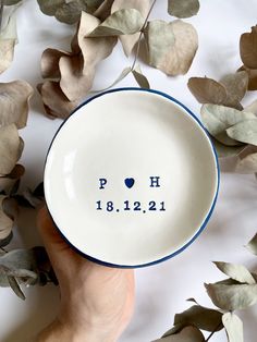 a person holding a small bowl with the word poh on it in front of some leaves