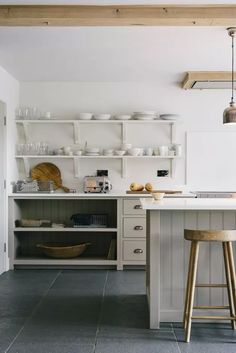 a kitchen with two stools in front of the counter and shelves on the wall