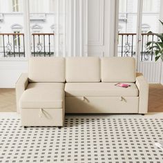 a white couch sitting on top of a rug in a living room next to a window