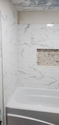 a white bath tub sitting inside of a bathroom next to a shower head mounted on a wall