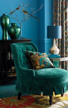 a living room with blue walls and furniture in the corner, including a green chair