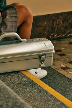 a person sitting on the ground with their legs crossed and a suitcase in front of them