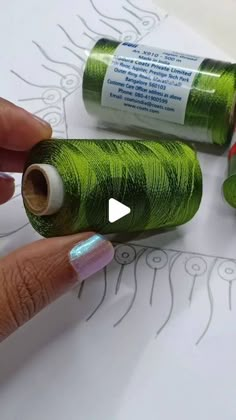 two rolls of green thread sitting next to each other on top of a sheet of paper