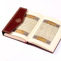 an open book with arabic writing on the pages and a red cover sitting on a white surface