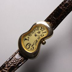 "1990s Salvador Dali museum softwatch Arabic Markers 💛Champagne  dial / Gold case 🤍Clear crystal 🖤Arabic numerals 🤍Stainless stell back 💛Original melting buckle 🤎Original leather strap used Authentic from salvador dali museum Pre-Owned Some scratch but in Very good conditions Dimension Case 🔽 High 38mm x width 24 mm Conditions 80% (The strap was used and the old one has been collected Rugged operation is not guaranteed) Because it is a watch that is almost thirty years old have some minor scratches on case (can polished) but still in working condition ✅This listed come only watch with melting buckle and strap✅ Please decide from the picture. Sold as is Some people ask questions about the product after they have made a successful purchase.  But be sure to ask \"before buying\" if you Old Watches Vintage, Melted Watch, Salvador Dali Watch, Dali Jewelry, Dali Watch, Aesthetic Watch, Salvador Dali Museum, Dali Museum, Watch Old