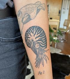 a person with a tattoo on their arm holding a fish and jellyfish in front of them