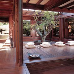 a wooden deck with pillows and a potted tree