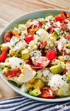 a salad in a bowl with tomatoes, cucumbers, and other toppings