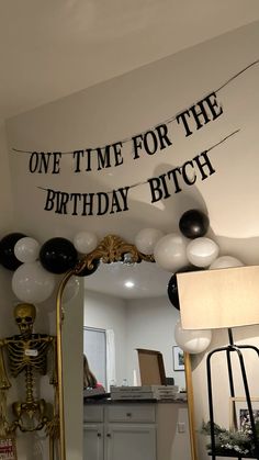 a birthday party with balloons on the ceiling and a skeleton in the mirror behind it