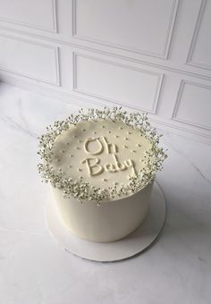 a white cake with the words on baby written in frosting and sprinkles