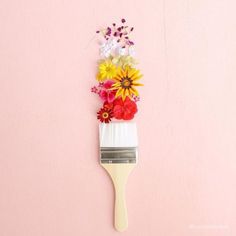 a paintbrush with flowers on it against a pink background