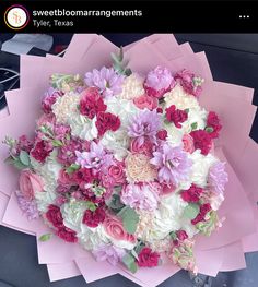 a bouquet of flowers is sitting on top of pink envelopes in the back seat of a car