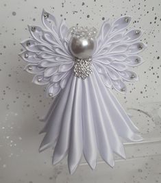 an ornament made to look like a white angel with pearls on its wings