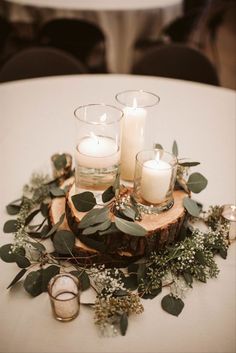 there are candles on the table with greenery around it and some rings in front of them