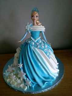 a blue and white cake with a doll on top