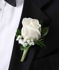 a white rose and baby's breath boutonniere on a black suit