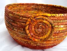 a close up of a woven basket on a white tablecloth with an orange and yellow flower in the center