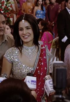 a woman in a red and white sari sitting next to a man wearing a suit