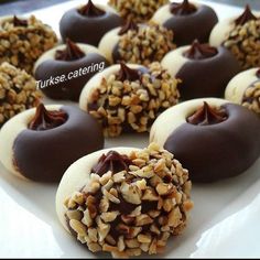 chocolate covered donuts with nuts and sprinkles on a white plate