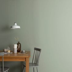 a wooden table with two chairs and a white light hanging from the ceiling over it